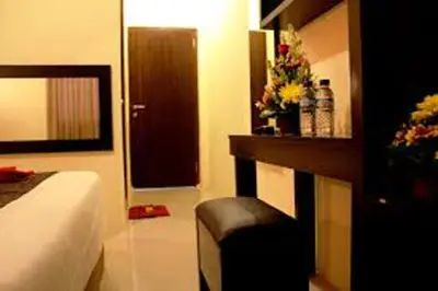 a bedroom with a bed and a bench with flowers on it at Asher Bali Transit in Kuta