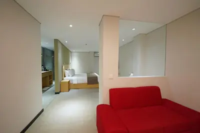 a red couch in a room with a bedroom at Episode Kuta Bali in Kuta
