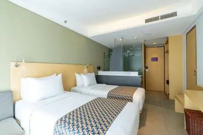 a hotel room with two beds and a bathroom at Episode Kuta Bali in Kuta