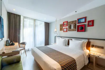 a hotel room with a large bed and a desk at Episode Kuta Bali in Kuta