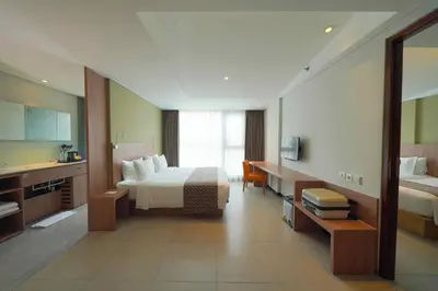 a large hotel room with a bed and a desk at Episode Kuta Bali in Kuta