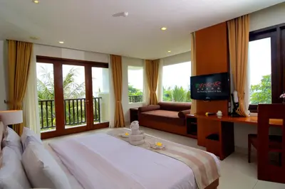 a bedroom with a bed and a couch and a television at Bali Relaxing Resort and Spa in Nusa Dua