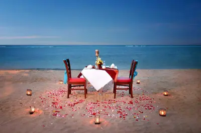 a table and chairs on the beach with candles at Bali Relaxing Resort and Spa in Nusa Dua