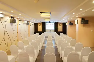 a conference room with white chairs and a projection screen at Bali Relaxing Resort and Spa in Nusa Dua
