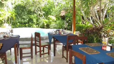 a table with blue tables and chairs and a pool at Adus Beach Inn in Legian