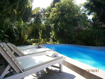 a swimming pool with two lounge chairs next to a swimming pool at Adus Beach Inn in Legian