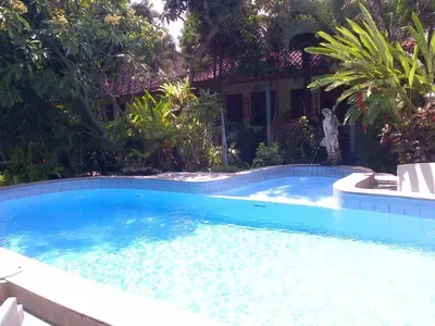 a large blue swimming pool with a man standing next to it at Adus Beach Inn in Legian
