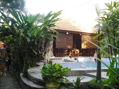 a resort with a swimming pool with people in it at Adus Beach Inn in Legian