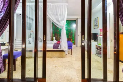a bedroom with a bed with purple curtains and a window at Lavender Villa & Spa in Kuta