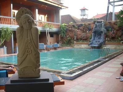 a statue in front of a swimming pool at Hotel Sorga Cottages in Kuta