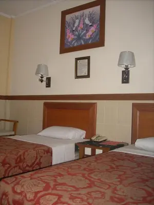 a hotel room with two beds and a picture on the wall at Hotel Sorga Cottages in Kuta