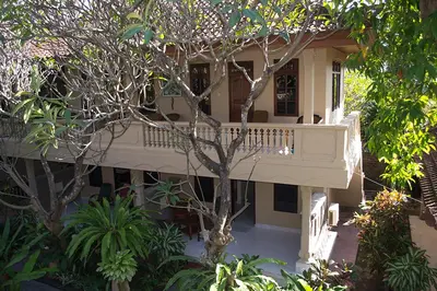 a building with a balcony in the middle of trees at Flamboyan Hotel in Kuta