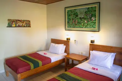 a room with two beds and a painting on the wall at Flamboyan Hotel in Kuta