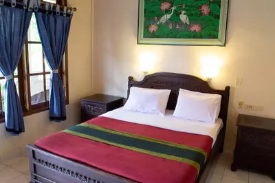 a bedroom with a bed with a painting on the wall at Flamboyan Hotel in Kuta