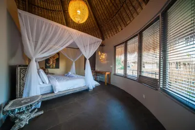 a bedroom with a bed with curtains and windows at Luxury Villas Merci Resort 3BR Seminyak #2 in Kuta