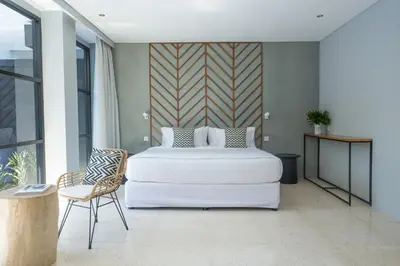 a bedroom with a large white bed and a chair at Origin Seminyak in Seminyak