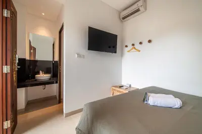 a bedroom with a bed and a television on the wall at Gelatik Bed And Breakfast in Seminyak