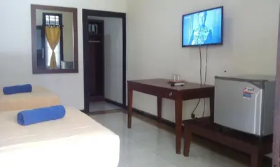 a bedroom with a bed and a tv and a desk at Bali Diva Hotel Kuta in Kuta