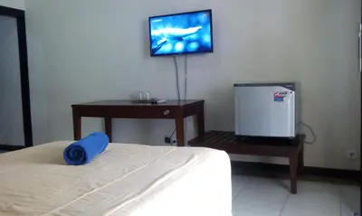 a bedroom with a bed and a tv on the wall at Bali Diva Hotel Kuta in Kuta