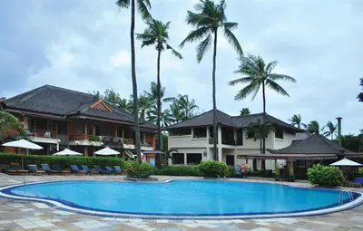 a swimming pool in front of a resort with palm trees at The Jayakarta Bali Beach Resort in Legian