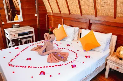 two dolls are laying on a bed with flowers on it at Kubu Kak Dudung Villas in Jimbaran