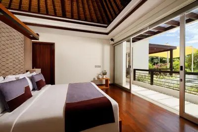 a bedroom with a large bed and a balcony at Villa Camellia by Nakula in Jimbaran