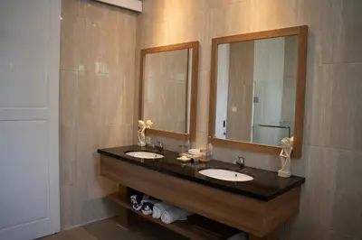 a bathroom with two sinks and two mirrors at Awila Villas Kuta by The Wina Resorts in Legian