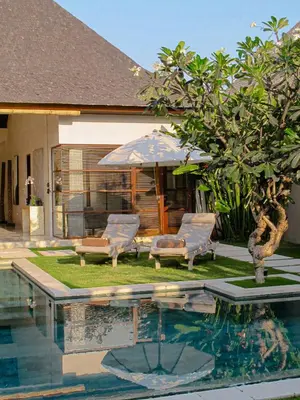 a swimming pool with two chairs and an umbrella at Nyaman Villas Seminyak in Seminyak