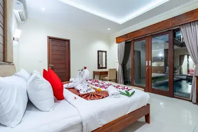a bedroom with a bed with red and white pillows at De' Bharata Bali Villas in Seminyak