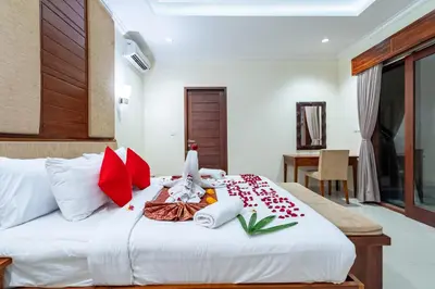 a bedroom with a bed with red and white pillows at De' Bharata Bali Villas in Seminyak