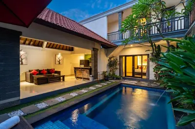 a villa with a swimming pool and a living room at De' Bharata Bali Villas in Seminyak