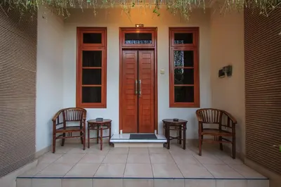 a porch with two chairs and a red door at Pondok Anyar Hotel in Kuta