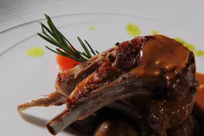 a piece of meat with sauce on a white plate at Amaroossa Suite Bali in Nusa Dua