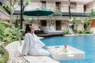 a woman sitting on a bench next to a pool at Amaroossa Suite Bali in Nusa Dua