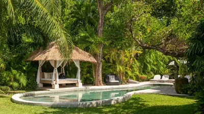 a swimming pool with a gazebo and chairs at Villa Koyama by Villa Finder in Seminyak