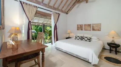 a bedroom with a bed and a desk and a window at Villa Koyama by Villa Finder in Seminyak