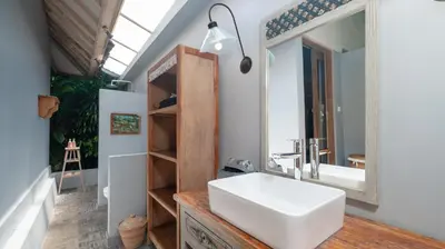 a bathroom with a white sink and a mirror at Villa Koyama by Villa Finder in Seminyak
