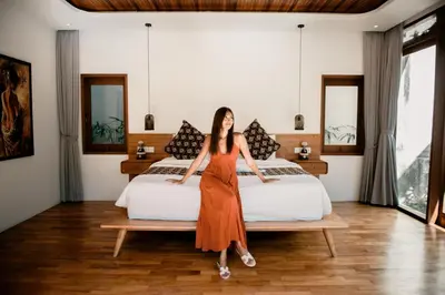 a woman in an orange dress standing in front of two beds at Luxury Villa Seminyak near beach and Potato Head in Seminyak