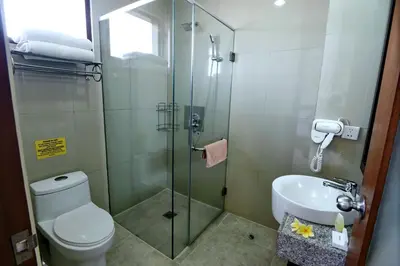 a bathroom with a shower and a toilet and a sink at Kuta Town House Apartments in Kuta