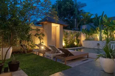 a backyard with chairs and a swimming pool at night at VILLA DUNA Seminyak Bali in Seminyak