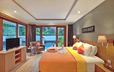 a bedroom with a large bed and a television at Kubu GWK Resort in Jimbaran