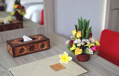 a table with a vase of flowers and a mirror at Kubu GWK Resort in Jimbaran
