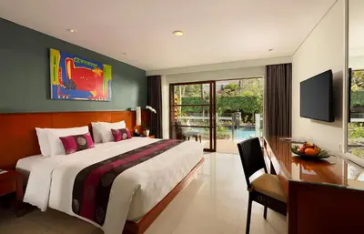 a bedroom with a bed and a desk and a television at Bali Dynasty Resort in Kuta