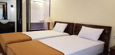two beds in a hotel room with a mirror at Eddys Cottages & Villa in Legian