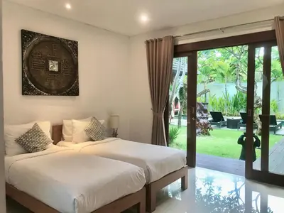 a bedroom with a bed and a sliding glass door at Nil Villa Seminyak in Seminyak