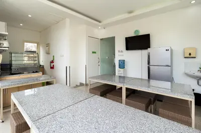 a kitchen with two tables and a refrigerator at Ara Inn Bed And Breakfast by ecommerceloka in Kuta