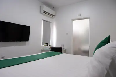 a bedroom with a white bed and a flat screen tv at Ara Inn Bed And Breakfast by ecommerceloka in Kuta