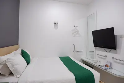 a bedroom with a bed with a tv on the wall at Ara Inn Bed And Breakfast by ecommerceloka in Kuta
