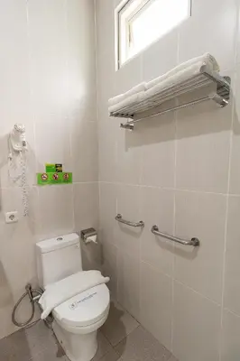 a bathroom with a white toilet and a window at Ara Inn Bed And Breakfast by ecommerceloka in Kuta
