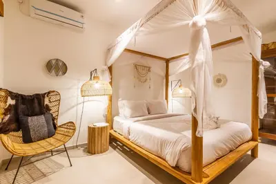 a bedroom with a canopy bed and a chair at Villa Namu by Alfred in Bali in Seminyak